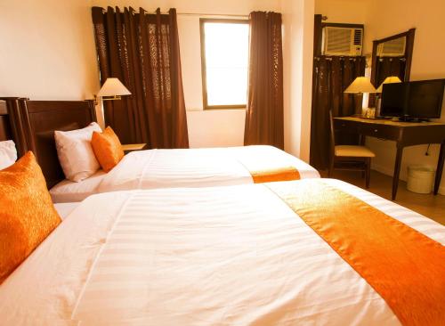 a hotel room with two beds and a desk at Harbor Town Hotel in Iloilo City
