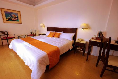 a hotel room with a large bed and a desk at Harbor Town Hotel in Iloilo City