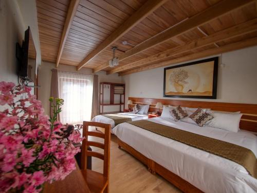 a hotel room with two beds and a vase of flowers at Sol Ollantay Exclusive Hotel in Ollantaytambo