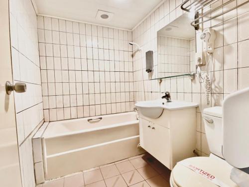 a bathroom with a toilet and a tub and a sink at WL HOTEL Hsinchu in Hsinchu City