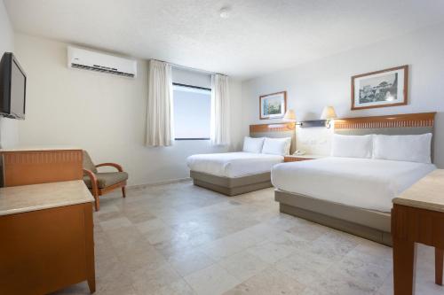 a hotel room with two beds and a television at Gamma Villahermosa Centro in Villahermosa