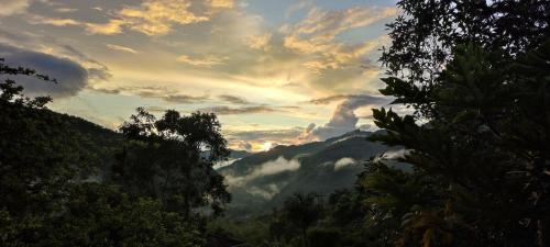 a sunset in the mountains with trees and clouds at Colibamboo Domo Glamping in Pacho