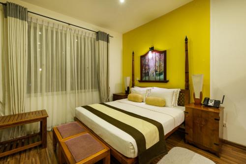 a bedroom with a large bed with yellow walls at Morning Dew Boutique Hotel Ella in Ella