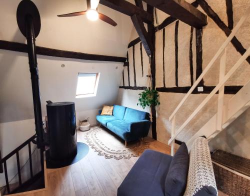 een woonkamer met een blauwe bank en een plafondventilator bij Loft atypique au calme avec cour privative in Bourges
