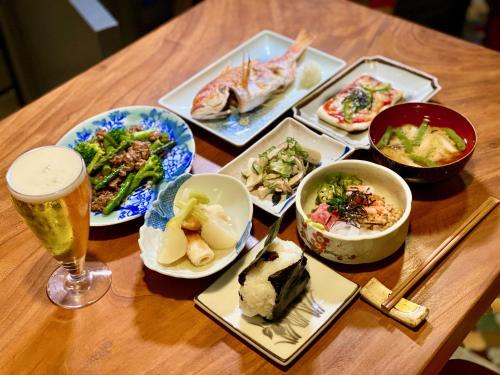 a table with plates of food and a glass of beer at Andon Ryokan in Tokyo