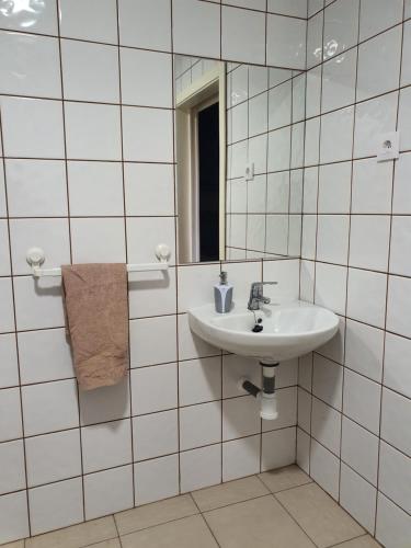 a white tiled bathroom with a sink and a mirror at Albergue la Fontanina in Mata de Alcántara