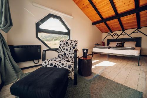 a bedroom with a bed and a chair and a window at Wild nest Deer Lux in Zlatibor