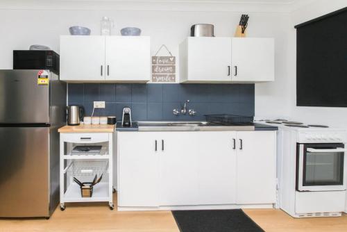 a kitchen with white cabinets and a stainless steel refrigerator at Modern Apartment Close to the City Centre 16 in Cairns