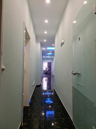 a hallway with a tile floor and a hallway with blue lights at Hotel Sofia in Bad Wildungen