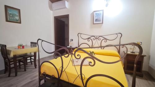 ein gelbes Bett in einem Zimmer mit einem Tisch in der Unterkunft Camera matrimoniale 1 per vacanza al mare VILLA FRANCA in Cariati