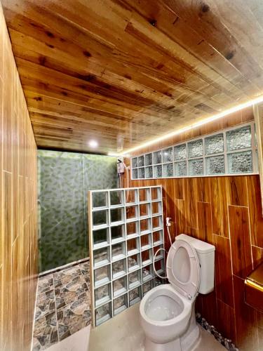 a bathroom with a toilet with a wooden ceiling at Noree Deluxe in Ban Phan Sadet Nai