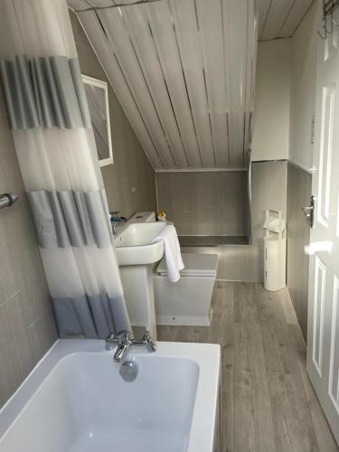 a small bathroom with a tub and a sink at Busby Apartments in Carmunnock