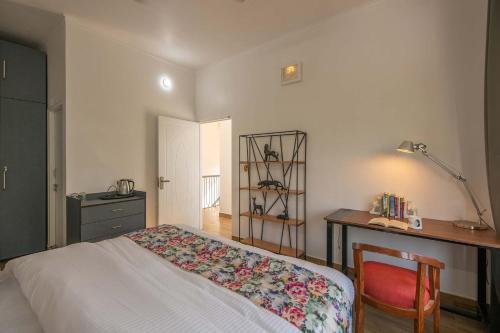 1 dormitorio con cama, escritorio y silla en StayVista at Pines & Fir - Sprawling Gardens with Seating and Swings, en Lansdowne