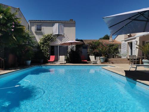 ein großer blauer Pool vor einem Haus in der Unterkunft Gîtes, Chambres d'Hôtes La Maison d'Amis in Puilboreau