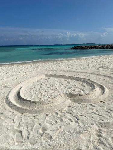 a peace sign in the sand on a beach at Lea Spa Hotel in Maafushi
