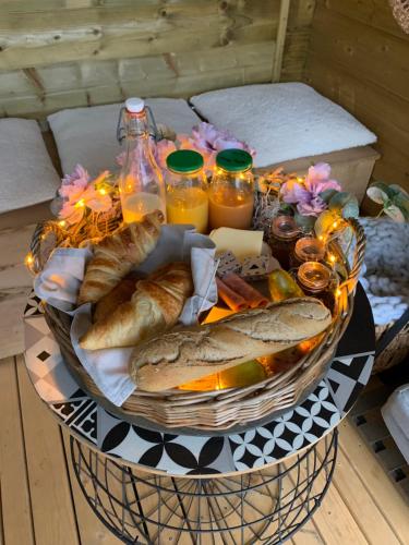 a basket of bread and orange juice and some drinks at Cabane au style scandinave et son bain nordique in Bouillon