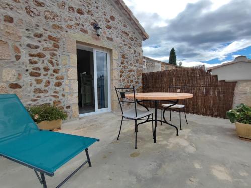un patio avec une table et des chaises en bois dans l'établissement Le Mas de la Charrette, à Vinezac
