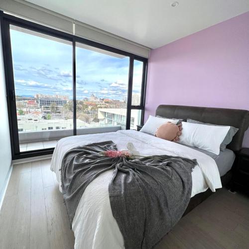 Carlton Stunning View Apartment 150m away from University of Melbourne في ملبورن: غرفة نوم بسرير كبير وبجدار ارجواني