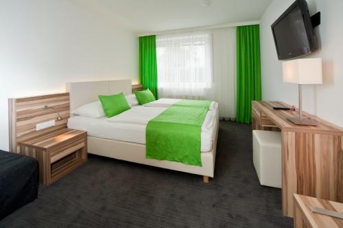 a bedroom with a bed with green sheets and a television at Happy Lake by Thomas Strugger in Krumpendorf am Wörthersee
