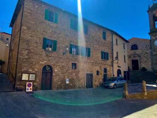 ein großes Backsteingebäude mit einem davor geparkt in der Unterkunft Dimora Toscana in Seggiano