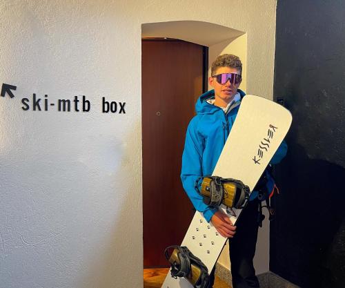 a man standing in a hallway holding a snowboard at Alp Apartments SKI & BIKE - Tourneuve5 in Aosta