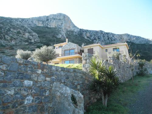 a house behind a stone wall with a mountain in the background at Villa Cazala in Monemvasia