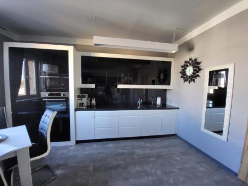a kitchen with white cabinets and a black appliances at Lupus Apartamenty in Poznań