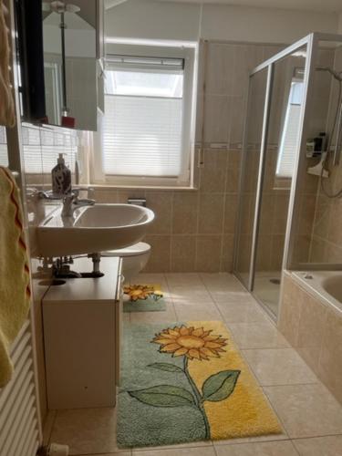 a bathroom with a sink and a mirror and a shower at Ferienwohnung Maier in Kreenheinstetten