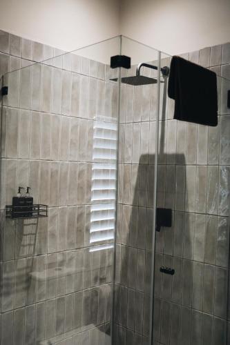 a bathroom with a shower with a glass door at The Oyster Box Beach House by The Oyster Collection in Kenton on Sea