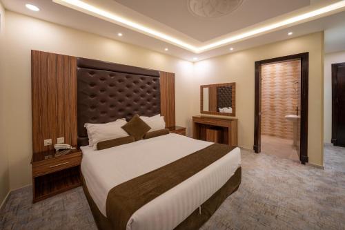 um quarto de hotel com uma cama grande e uma casa de banho em The Palace Hotel Suites em Abha