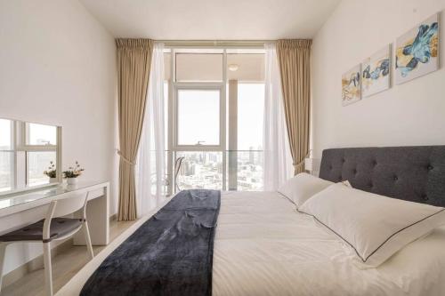 a bedroom with a bed with a desk and a window at High floor 1BR vacation home with terrace in Dubai