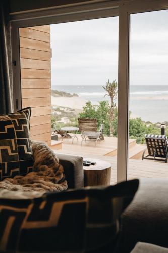 a living room with a couch and a view of the beach at The Oyster Box Beach House by The Oyster Collection in Kenton on Sea