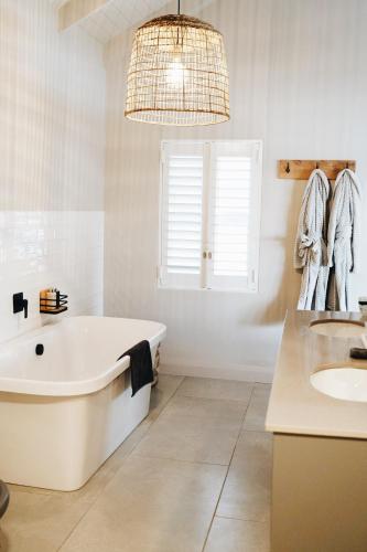 a white bathroom with a tub and a sink at The Oyster Box Beach House by The Oyster Collection in Kenton on Sea