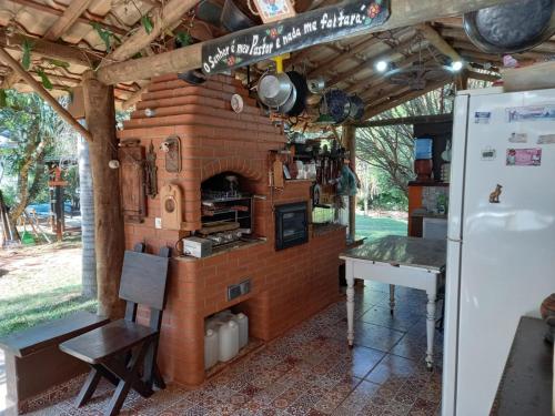 um forno de tijolo com uma mesa e um frigorífico em Casa de campo serrana, alegre e com piscina em Lindoia