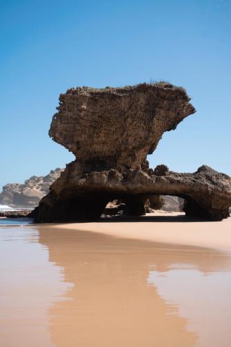 a large rock formation on a beach with water at The Oyster Box Beach House by The Oyster Collection in Kenton on Sea