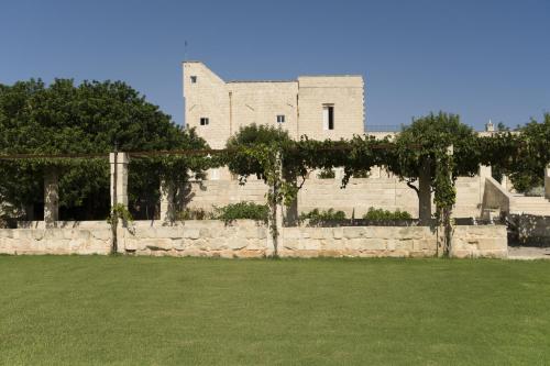 a building with a stone wall and green grass at MASSERIA LILEI in Lizzanello