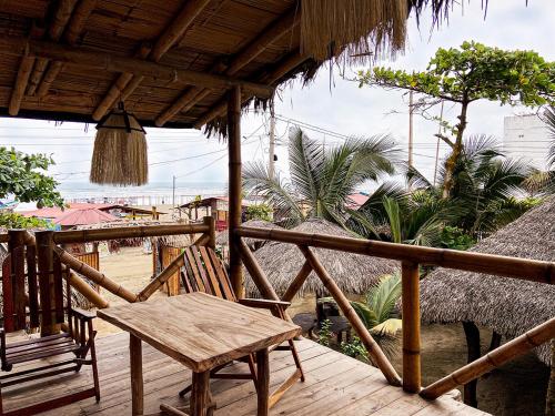 una terraza de madera con banco y techo de paja en Hostal Olmito Canoa en Canoa