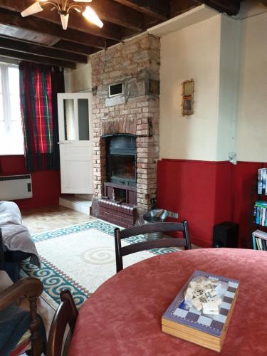 a living room with a fireplace and a table with a book at Saint Cyr du Bailleul - Maison in Saint-Cyr-du-Bailleul