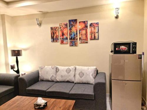 a living room with a couch and a refrigerator at Comfortable & Lovely 1 Bed Apt In Bahria Town in Rawalpindi