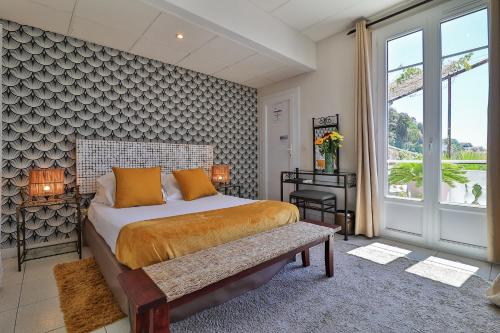 1 dormitorio con cama, banco y ventanas en Le Panoramic Boutique Hôtel, en Niza
