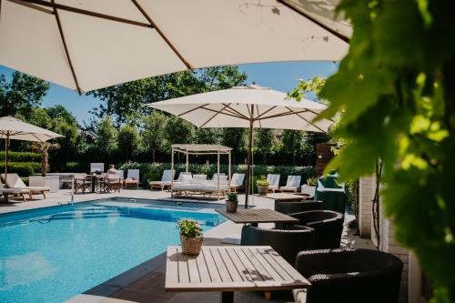 a swimming pool with umbrellas and tables and chairs at Badhotel Renesse in Renesse