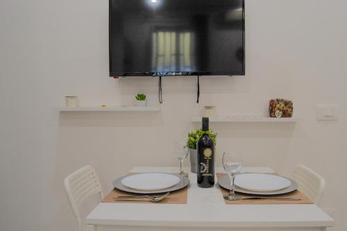 a table with plates and glasses and a bottle of wine at Manfredi Apartments in Torre Annunziata
