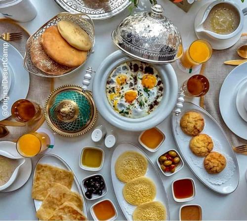 a table topped with plates and bowls of food at Sahara Luxury Tented Camp in Merzouga