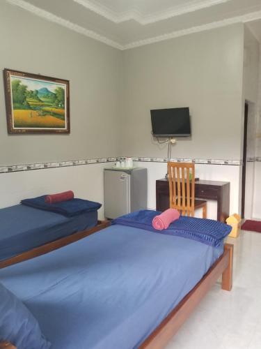 a bedroom with two beds and a tv and a chair at Jepun Segara Guest House in Kuta