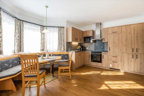 una cocina con armarios de madera, mesa y sillas en Appartements Baumanngut, en Wagrain