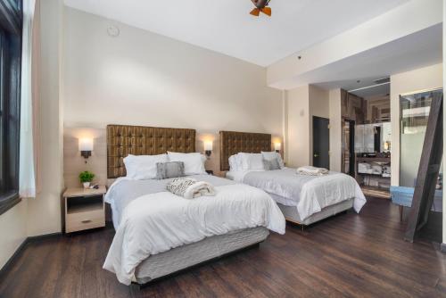 a bedroom with two beds with white sheets and wood floors at Good Hotels Downtown Denver in Denver