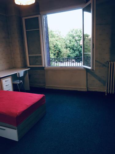 une chambre avec un lit rouge et une grande fenêtre dans l'établissement Comfortable Paris 1, à Vitry-sur-Seine