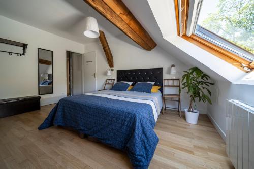 a bedroom with a bed with a blue comforter and a window at La Maison de Beaume in Créancey