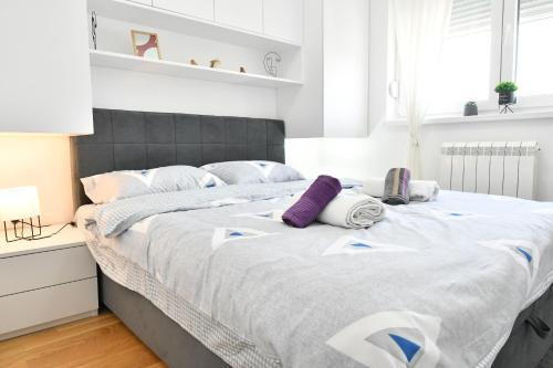a bedroom with a large bed with white and purple pillows at Apartman Daniela in Lukavica
