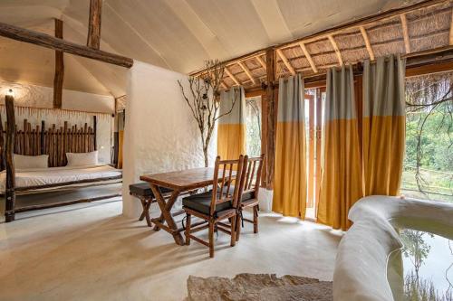 a room with a table and chairs and a bed at Deshadan Eco Valley Resort - An Eco friendly Mud House in Kanthalloor